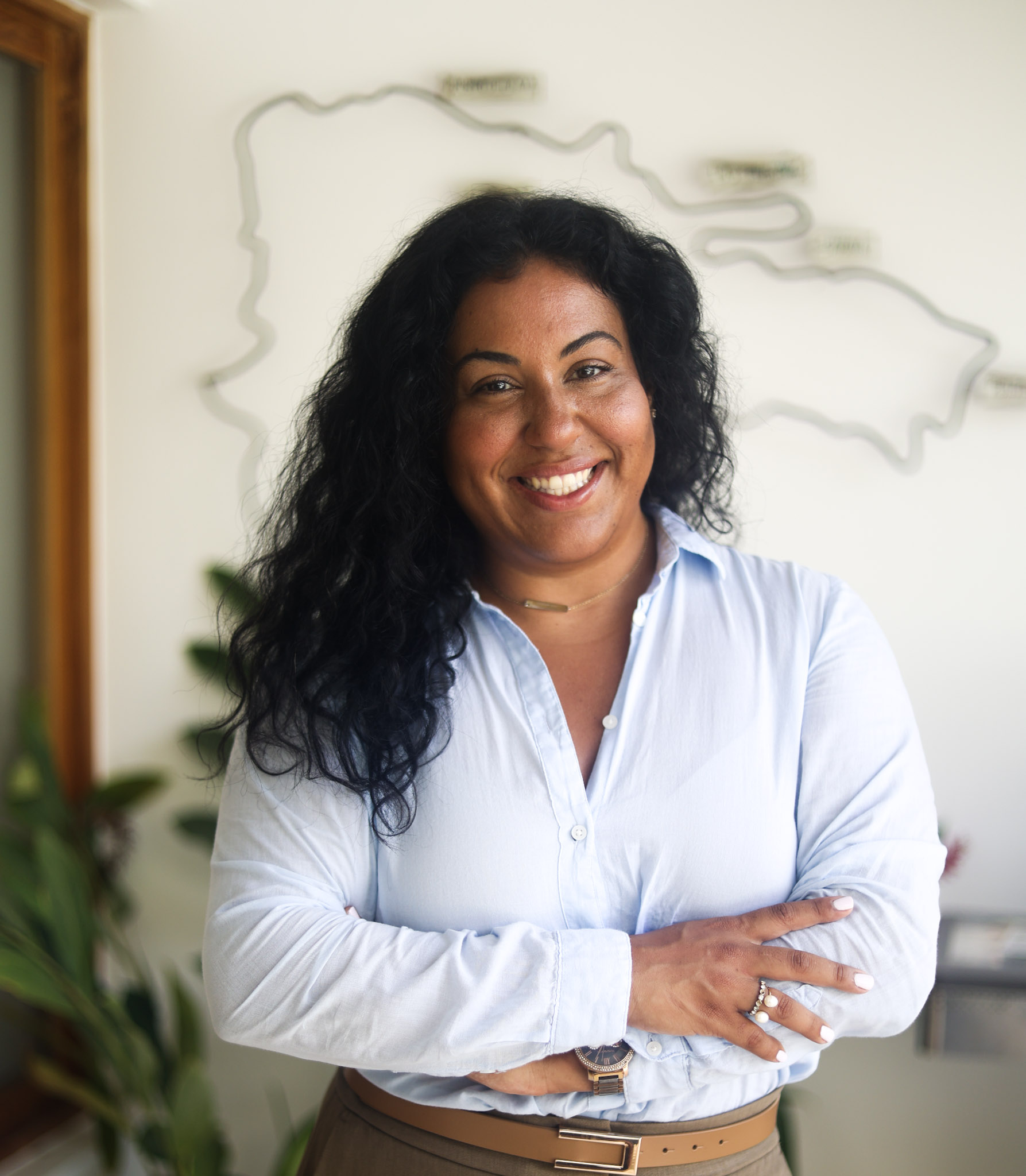 Lynnette Diaz smiling, standing in a warm office with plants and natural light